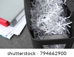 Document shredder with paper shreds on table, closeup
