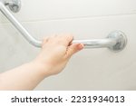 hand holding the handrail in the shower, safe bathing for the elderly and people with limited mobility
