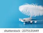 Small photo of airplane and feather on a blue background, soft landing, easy and comfortable flight