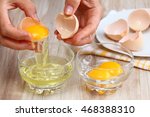 Woman hands breaking an egg to separate  egg white and  yolks and egg shells at the background  