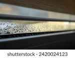 Small photo of Indoor close-up of a leaky window with steam and condensate texture.