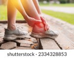 Small photo of female joggers pain and discomfort after running in the public park. care and treatment for ankle injuries concept.