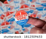 Finger with I Voted button in front of voting stickers given to US voters in Presidential election to illustrate vote suppression or rejections