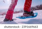 Small photo of LENS FLARE, CLOSE UP Unrecognizable lady is running with snowshoes on fresh snow on a beautiful sunny winter day. White snowflakes spray and sparkle in sunlight as she lifts her feet while snowshoeing