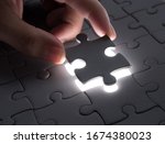 Small photo of Hand embed missing puzzle piece into place with light glow,success, teamwork and finishing or ending