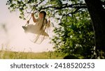 Child plays on wooden swing ...