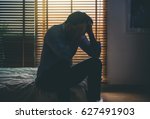 depressed man sitting head in hands on the bed in the dark bedroom with low light environment, dramatic concept