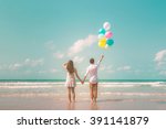 Portrait of couple of young happy married hipsters in trendy vintage clothes standing together on the beach with balloons. Sunny summer day. Pastel colors tone 