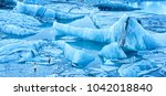 Small photo of Jokulsarlon glacier lagoon panorama at dawn, in Iceland. Unidentifiable tourists walk on thin ice to photograph spectacular icebergs.