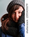 Small photo of spirited young woman loves her winter fashion. Dressed in wool gloves, hat, scarf, and snug sweaters, she's warm despite the chill. Her long brown hair and bright eyes are captivating