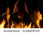 Small photo of Fire and flames surround the portrait of an arsonist. He is wearing a hooded shirt. The background is black.