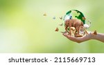 Small photo of Earth Day or World Wildlife Day concept. Save our planet, protect green nature and endangered species, biological diversity theme. Group of wild animals and flock of butterflies with globe in hand.