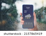 woman using smart phone with weather forecast on screen.