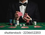 Crop picture of close up man dealer or croupier shuffles poker cards betting in casino on black background of green table, Dealer man invitation bet playing cards. Casino, poker, poker game concept