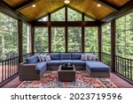 New modern screened porch with patio furniture, summertime woods in the background.