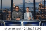 Small photo of Two newscasters smiling broadcasting news at television media channel closeup. Happy couple presenters hosting newscast standing stage tv studio. Charismatic anchors talking collaborating in air