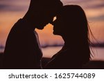 Silhouette of young couple having romantic moments against the sunset background. Silhouette of romantic couple stand huggins