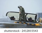 Small photo of A pilot and co pilot in a G-suit inspects a fighter jet. Control panel area on the side of the aircraft fuselage. Check readiness before flying.