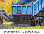 Dump truck, tractor and bulldozer unloading gravel, road metal and crushed stone cement material during landscaping improvement and new pedestrian walk road construction site