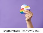 Small photo of Hand raising three pins with rainbow, trans and non binary flags, on a purple background. Concepts of LGBT identity pride, gender diversity visibility, equality and non discrimination.