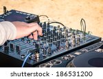 Hand of a deejay playing music on professional mixing controller at the beach