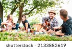 Small photo of Friends group having fun moment at pic nic playing guitar on sunset - Friendship life style concept with young people enjoying springtime camping together at park location - Bright greenish filter