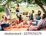 Fancy people laughing at vineyard place after sunset - Food and beverage concept with men and women drinking wine at barbeque party - Happy friends camping at open air pic nic on warm vivid filter