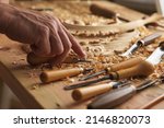 Small photo of Craftsman carving with a gouge. Woodwork. Workbench with equipment. Wood carving tools. Chisels for carving