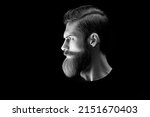 Small photo of Man portrait. Black and white dramatic light portrait of confident young bearded man looks into the distance. Stylish young man red beard. Light accent on the beard and hair
