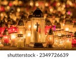 Candle lights on graves and tombstones at a cemetery in Poland during All Saints Day, Zaduszki day, and Day of the Dead. Lit candles illuminate the graves at a Christian cemetery at night.