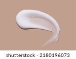White cosmetic cream lotion swatch smear smudge on brown color background.	