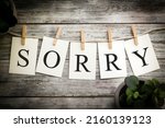 A set of printed cards spelling the word SORRY on an aged wooden background.