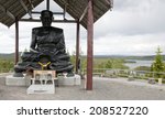 Small photo of FREDRIKA, SWEDEN ON JUNE 27. The Buddha Rama Temple on the top of the mountain on June 27, 2014 in Fredrika, Sweden. A dark bronze monk under cover, forest and lakes in the background.