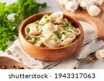 Homemade meat dumplings with onions and parsley- russian pelmeni in wooden bowl.
