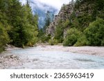 Pisnica valley in Triglav National Park, Kranjska Gora, Slovenia. Scenic landscape with river surrounded by wooded cliffs and misty Alps mountains, outdoor travel background