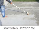 Small photo of Worker and renovation work. To using roller painting mortar cement or finishing material for repair crack, skim coat or improvement surface of concrete pavement floor or slab for driveway or garage.