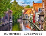 Small photo of Bruges, Belgium. Medieval ancient houses made of old bricks at water channel with boats in old town. Summer sunset with sunshine and green trees. Picturesque landscape.