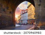 Prague, Czech Republic. Sunset in old town through medieval arch in Powder Gate tower of vintage european street. Scenic urban landscape with sun.