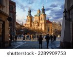 Prague, Czech Republic. View at the Saint Nicholas Church Staromestska square in centre of Prague Old Town. Evening sunset and people walking by street