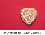 Gingerbread in the shape of a heart on red background