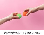 Woman hands holding colored Easter eggs for knocking on pink background. Easter celebration or creative concept. Adam creation