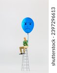 Small photo of Miniature people, A despondent businessman with a blue balloon is sitting on a staircase. , Blue monday concept. The most depressing day of the year.