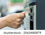 Small photo of Closeup of female hand with a credit card and ticket vending machine