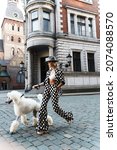 Small photo of Portrait of stylish woman wearing polka dot suit walking with the white Poodle
