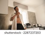 Small photo of Portrait of attractive male slob drinking whiskey in his kitchen