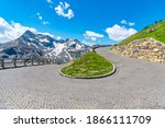 Mountain cobbled road serpentine. Sharp curve with mountain tops on background. High Tauern, Austria