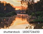 Scenic colourful sunrise over Macquarie river in Dubbo with pelikan birds floating on surface.
