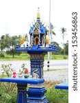 Small photo of Blue spirit house in thailand with flowers in vases and some wreathes, joss house