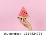 Hand holding slice of ripe watermelon on pink background