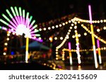 Blurry rollercoaster in bokeh, Ferris wheel at night of colorful with outdoor, Defocused (blurred) and blur image of Amusement park, The annual temple event has activities. Image out of focus